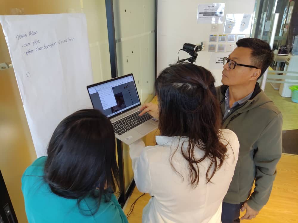 Small-group workshop working through a funnel on a flipchart, participants at laptops